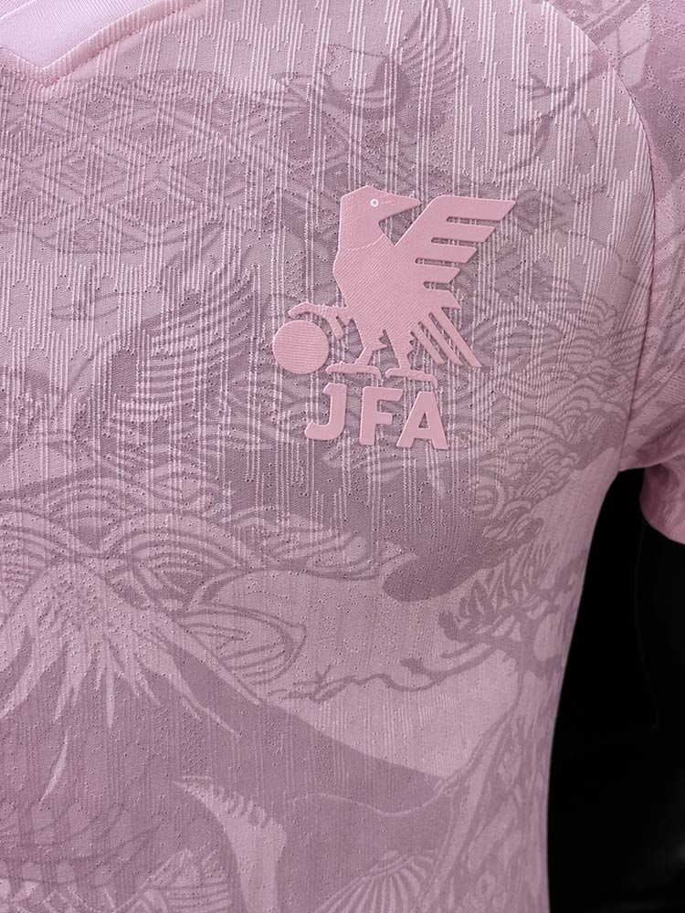 Gros plan sur le blason JFA du maillot Fuji Rose - corbeau yatagarasu et lettres JFA en relief ton sur ton rose, motifs floraux japonais visibles sur le tissu