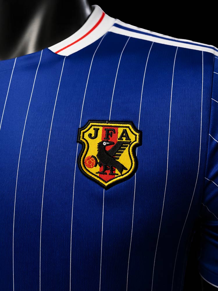 Gros plan sur le blason JFA brodé du maillot du Japon Vintage - écusson doré avec le corbeau yatagarasu sur fond bleu à rayures